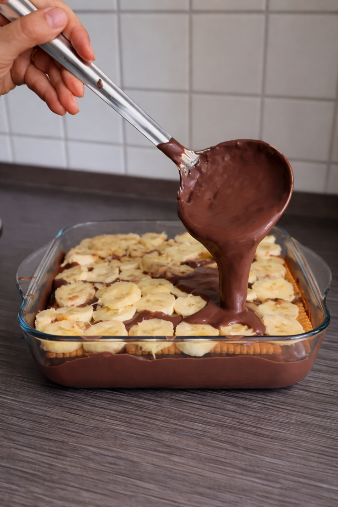 Čoko biskvit kolač sa bananama i toplim čokoladnim sosom koji se preliva preko keksa