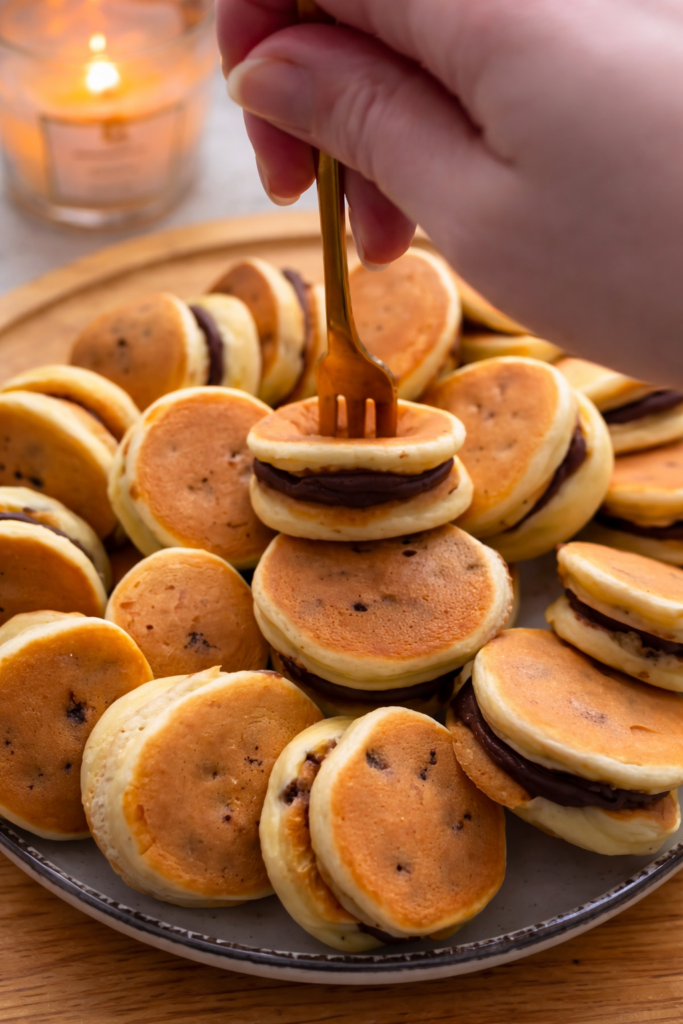 Mini palačinke od zobenih pahuljica i banane punjene čokoladnom kremom, servirane na tanjiru. Zdrav i jednostavan recept za doručak ili lagani desert bez bijelog brašna.